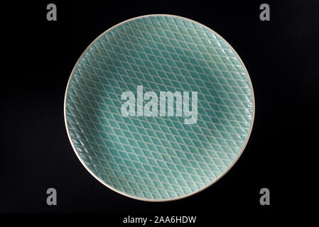A dark green ceramic plate with a diamond-shaped cross-line stripe Stock Photo