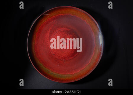 A dark red ceramic plate with a brown vintage pattern Stock Photo
