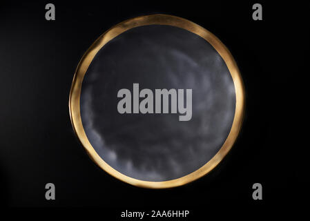Textured dark grey ceramic plate with gold rim Stock Photo