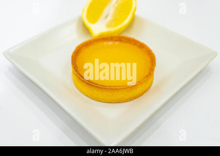 Lemon Curd Tart on plate. Home made freshly baked food. White background, no human. Empty copy space for text. Stock Photo