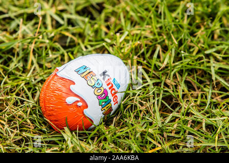 Kinder Surprise egg consists of a chocolate shell, plastic capsule with toy, and external foil wrap. Word Surprise written in Polish. made by Ferrero Stock Photo