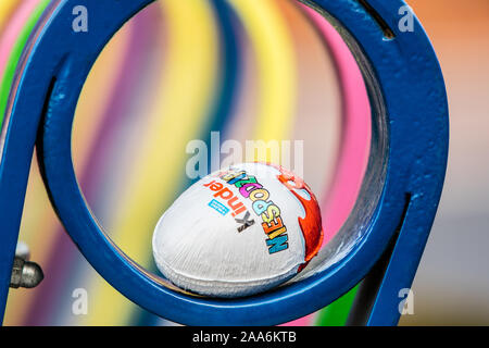 Kinder Surprise egg consists of a chocolate shell, plastic capsule with toy, and external foil wrap. Word Surprise written in Polish. made by Ferrero Stock Photo