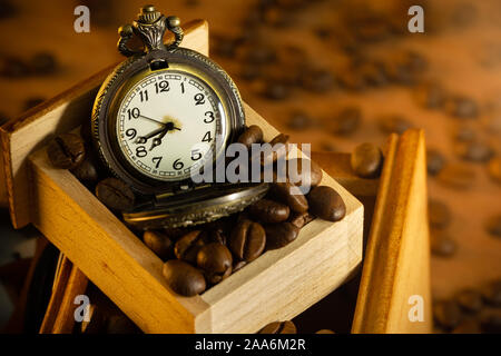 Coffee bean and pocket watch in manual grinder on table. Closeup and copy space. Concept of coffee time in morning. Stock Photo