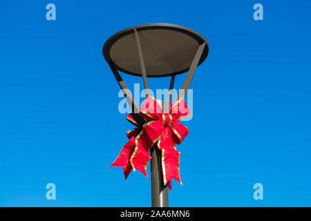 Christmas holiday bow on street light against blue cloudless sky Stock Photo