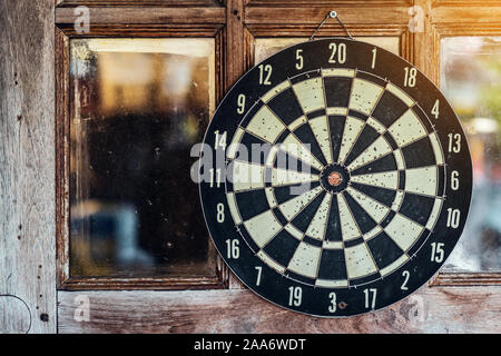 An old darts target hanging on old glass and wooden door. Stock Photo