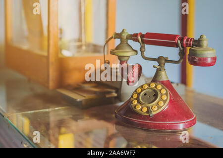 A red telehones with rotary dial with dust and scratches and credit card machine in ancient times placed on a glass showcase in an old gold shop in As Stock Photo