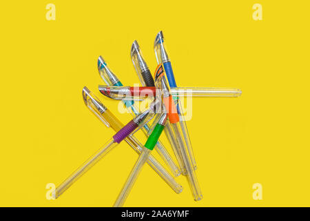 pile of colored pens lying on a yellow background Stock Photo