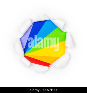 Paper hole in white paper with ragged edges with range of rainbow colors background. Isolated on white. Stock Photo