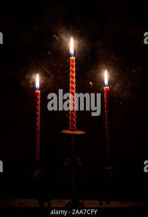 Three red candles burning in the darkness outside the window Stock Photo