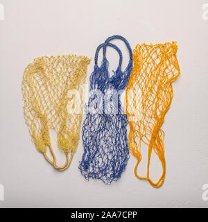 Concept of the three colored string bags made from natural materials on a light background. Environmental protection Stock Photo