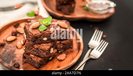 homemade, chocolate brownie with hazelnuts and almonds in a wooden plate Stock Photo