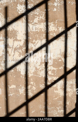 Shadow Pattern on Old Wall of Metal Bars or Iron-Barred Windows in Former Jail or Prison Cell Stock Photo