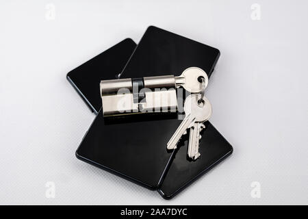 keychain with keys inserted in a lock on two black mobile phones on white background Stock Photo