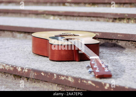 acoustic guitar, instrument lying on the steps of an old concrete slab acoustic string modern guitar, on the background of texture steps Stock Photo