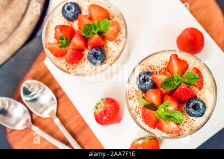 Homemade italian dessert tiramisu with strawberries, mint in glass jars, top view Stock Photo