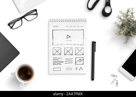 https://l450v.alamy.com/450v/2aa7fmx/sketch-of-a-website-on-a-paper-writing-pad-surrounded-by-smart-phone-cup-of-coffee-glasess-plant-office-desk-top-view-flat-lay-2aa7fmx.jpg