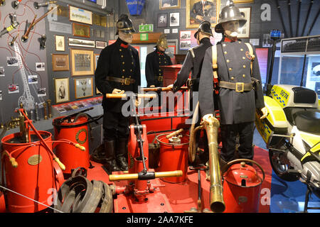 Fire Brigade Uniforms with old fire extinguishers and hoses. Police and Fire Heritage Collection, Solent Sky Museum, Southampton, Hampshire UK Stock Photo