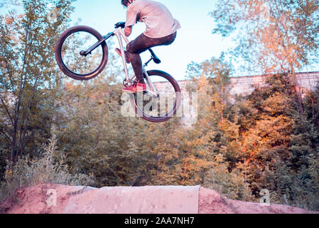 cool stunts performed by a professional cyclist-athlete. In a forest sports field, with ski jumps, jumping into the sky. Biking in the forest. Cycling Stock Photo