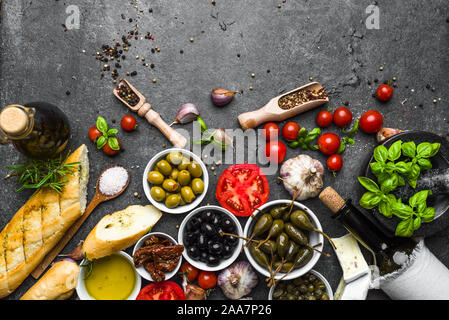 Italian food or mediterranean cooking ingredients. Herbs, olive, oil, tomato, bread, cheese and wine bottle. Stock Photo