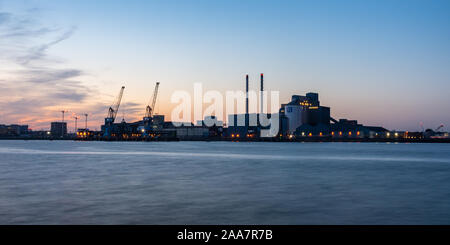 London, England, UK - September 21, 2019: The sun sets behind the industrial landscape of Tate and Lyle's sugar refinery in Silvertown, amid the apart Stock Photo