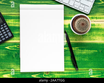 open notebook with white page, pen, calculator, computer keyboard, cactus  on  bright green weathered wooden table, top view Stock Photo