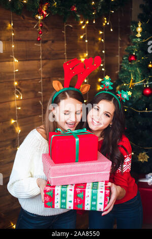 Cropped shot of a woman surprising her girlfriend with a Christmas gift. Stock Photo