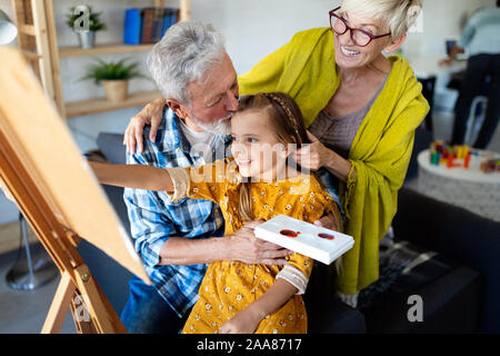 Happy grandparents and granddaughter drawing, painting together Stock Photo