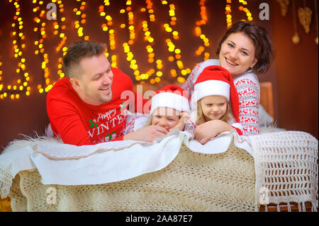 Portrait of a happy family. Sitting in pajamas on the bed and having fun. Christmas morning. Stock Photo