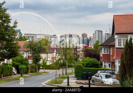 London, England, UK - July 7, 2019: The Wembley Stadium Arch and high rise new buildings appear over the suburban houses of Barn Hill in London. Stock Photo