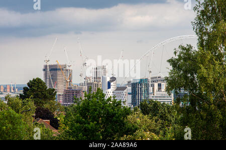 London, England, UK - July 7, 2019: The Wembley Stadium Arch and high rise new buildings appear over the trees of Barn Hill park in London. Stock Photo