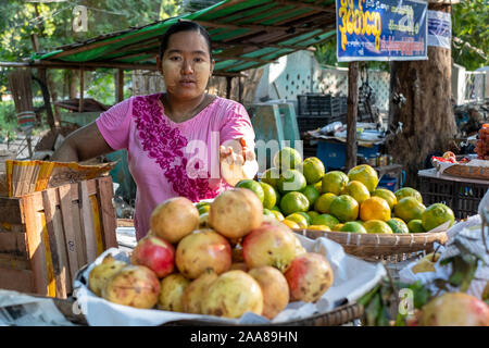 The lively meat,fish,vegetable & fruit market of Pakokku, Myanmar (Burma) with a young woman with face powder selling fresh apples and oranges Stock Photo