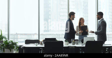 Businesspeople talking in office, standing against window Stock Photo