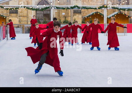 Winchester, Hampshire, UK. 20th November 2019. Choristers skating on the ice rink in their iconic red robes at Winchester Cathedral as Christmas festivities get underway with the festive tradition of the choristers skating around the rink ahead of its opening tomorrow. The ice rink is part of the Winchester Cathedral Christmas market, one of the biggest in the country. Credit: Carolyn Jenkins/Alamy Live News Stock Photo