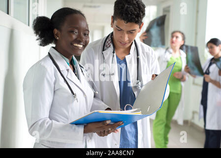 portrait of doctors, mixed race. A black girl, with a Mexican guy, in white coats, with stethoscopes, is holding medical documents, a consultation, a Stock Photo