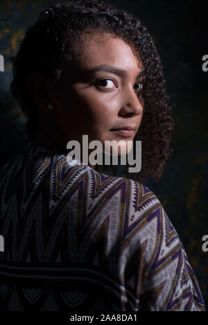 https://l450v.alamy.com/450v/2aa8da1/fashionable-portrait-of-a-beautiful-mexican-girl-with-curly-hair-flawless-skin-on-a-dark-abstract-background-dramatic-light-promotional-photo-2aa8da1.jpg