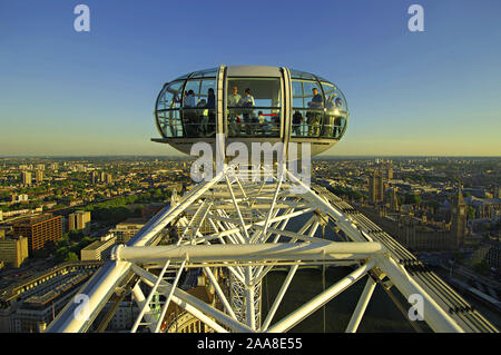 Close-up on a section of the main wheel and one of the passenger cabins on the London Eye at the top of its travel with an evening view of London behi Stock Photo