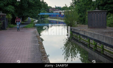 London, England, UK - June 18, 2017: A woman cycles along the towpath of the Grand Union Canal at Alperton in West London. Stock Photo