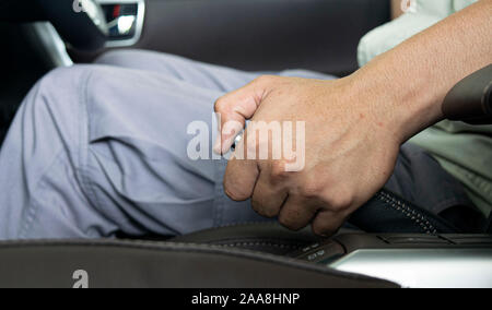 Male hand pulling a parking brake / Using a hand brake lever Stock Photo