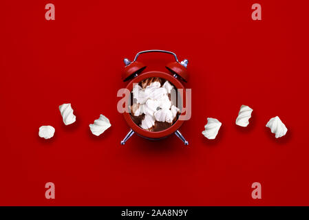 Alarm clock as cup of hot chocolate with marshmallow on red background. Top view. Flat lay.  Christmas and New Year holidays concept Stock Photo