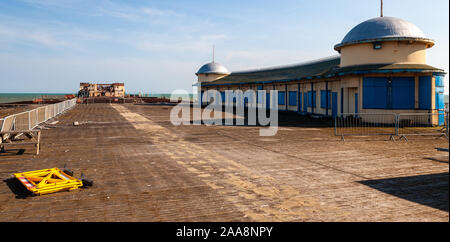 Hastings, England, UK - June 8, 2013: Damaged and derelict buildings are fenced-off of Hastings Pier prior to its refurbishment. Stock Photo