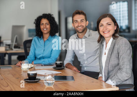 Smiling businesspeople sitting together at an office table Stock Photo