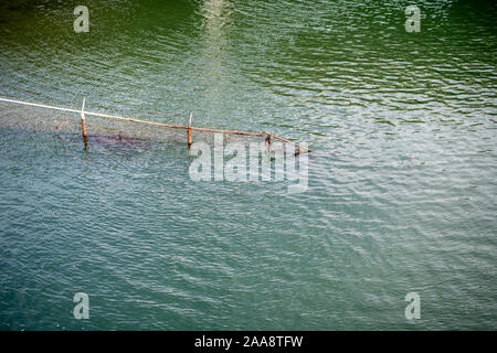 Rusty barbed wire fence descending into the bay Stock Photo