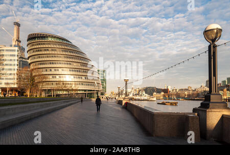 London, England, UK - March 3, 2011: Pedestrians walk past London's City Hall on the River Thames path early on a spring morning. Stock Photo