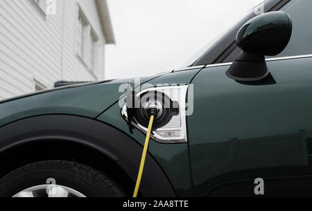 electric car lead plugged into an electric car at home Stock Photo