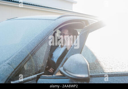 man sat in his frosty car talking on the phone leaving for work Stock Photo