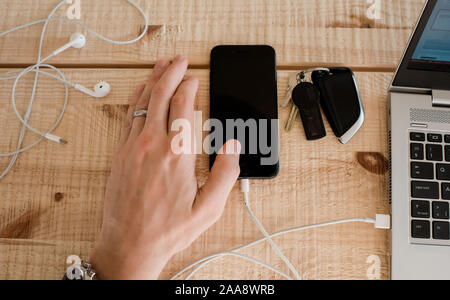 businessman's hand next to a phone, laptop, keys and headphones Stock Photo