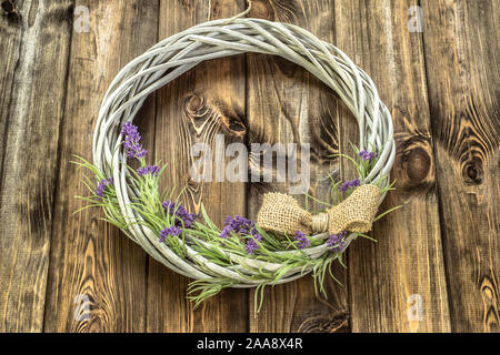 Braided wicker wreath with lavender flowers on wooden rustic