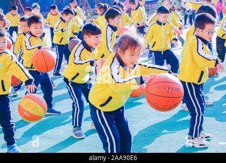 Young Chinese kids have fun with basketballs on the playground to mark the World Children's Day at a kindergarten in Motou Town, Rugao City, east Chin Stock Photo