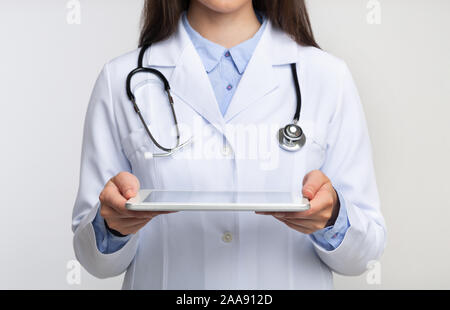 Unrecognizable Lady Doctor Holding Tablet Computer Standing, White Background, Cropped Stock Photo