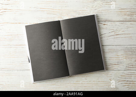 Opened empty book with black sheets on wooden background, space for text Stock Photo